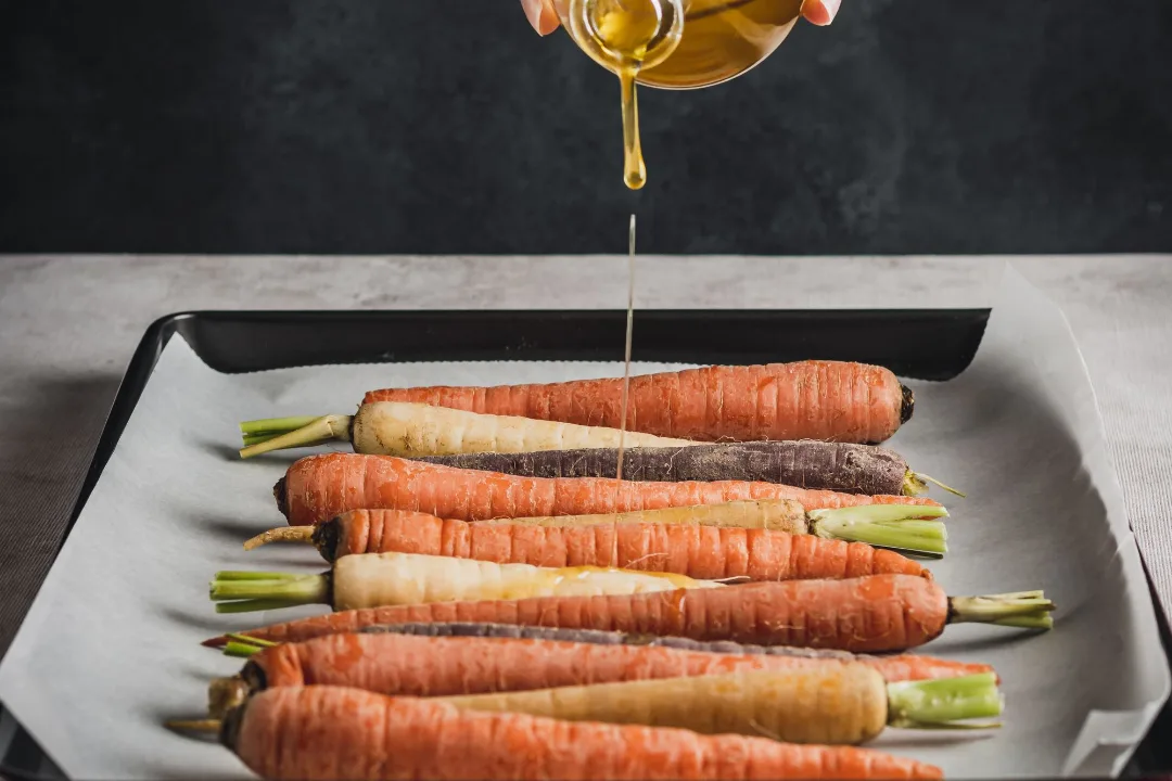 Filet d'huile d'olive versé sur des carottes entières, le détail qui maximise l'assimilation du bêta-carotène