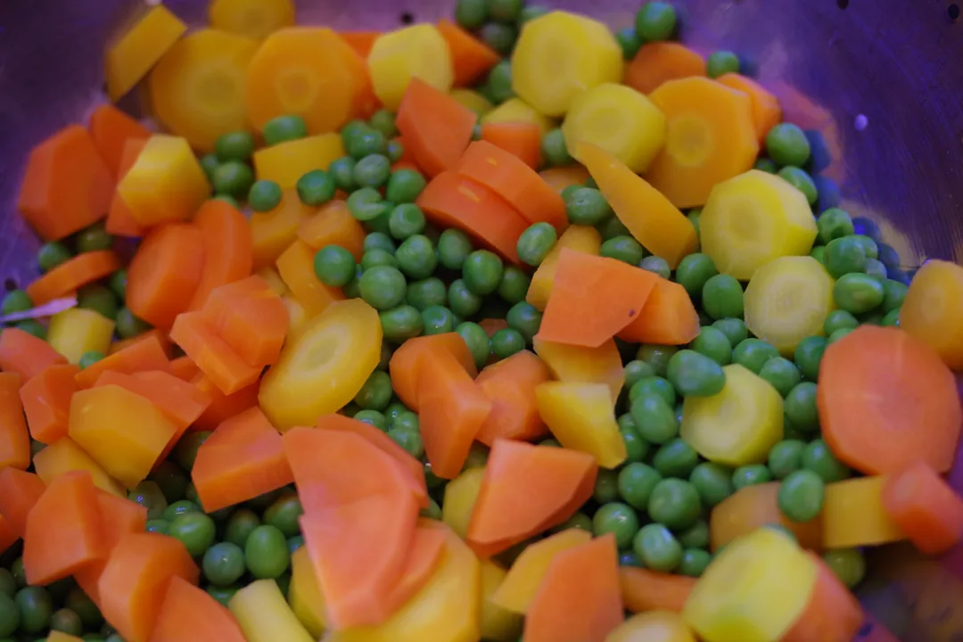 Petits pois et rondelles de carottes orange et jaunes cuits, mélangés en gros plan